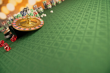 
Casino concept.  Roulette wheel, poker chips and dice on green table and on  yellow bokeh background.

