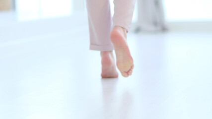 defocus, Side close up view of unrecognizable woman feet legs, barefoot girl standing indoors inside of modern home enjoy warm wooden heated floor. soft focus