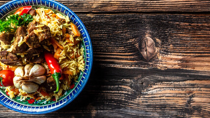 Traditional uzbek meal called pilaf. Rice with meat, carrot and onion in plate with oriental ornament, Uzbek oriental cuisine. Long banner format. space for text