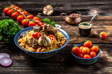 Traditional uzbek meal called pilaf. Rice with meat, carrot and onion in plate with oriental ornament, Uzbek oriental cuisine. Long banner format. space for text