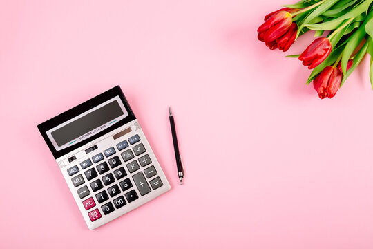 Bouquet of red tulips on pink paper background with calculator and pen are a template for advertising or visualization of blog with copy space for text. Business holiday card. Certificate mockup