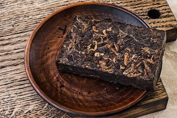 selective focus photo of a tile of palace puerh tea. chinese pressed black loose leaf tea shu puerh.