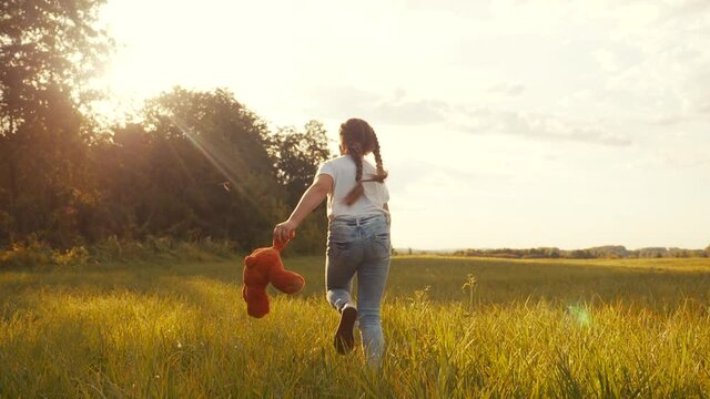 little girl with a teddy bear run in the park on the grass. happy family kid dream concept. little girl run in the park holding a teddy bear. happy childhood dream. kid fun walk in the park