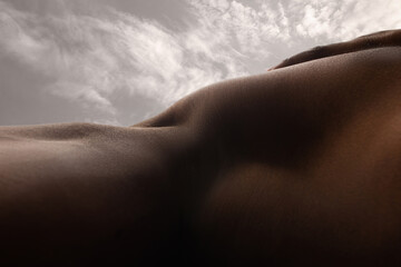 Higth. Detailed texture of human skin. Close up of young african-american male body surface like landscape with the sky on background. Skincare, bodycare, healthcare, inspiration, fantasy artwork.