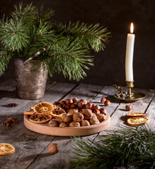 Christmas. Christmas tree, candle, walnuts, hazelnuts and dried oranges on a platter.