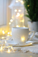Obraz na płótnie Canvas Coffee cup on the background of the Christmas garland