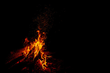 Fototapeta na wymiar Bonfire with sparks on a black background with free space