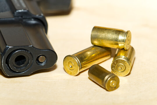 shell casings and barrel of a pistol close-up on a wooden table in a shooting range or at a crime scene. crime concept