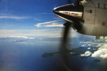 Naklejka na ściany i meble View on old vintage propeller plane with shiny chrome nose over tropical sea with islands - Philippines in the nineties
