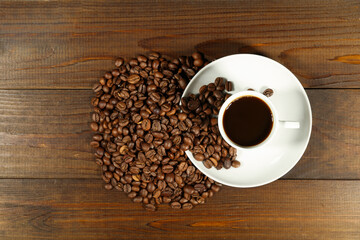 white coffee cup and coffee beans are on a wooden background. 