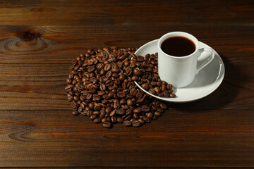 white coffee cup and coffee beans are on a wooden background. 