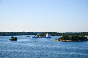 Obraz premium Ship sails through the small rocky islands of the Stockholm Archipelago in Sweden