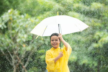 happy funny child with umbrella under the autumn shower. kid playing on the nature outdoors. girl...