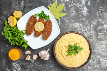 top view mashed potatoes cutlets parsley lemon slices turmeric on dark background