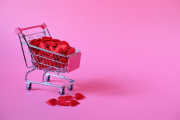 Shopping cart with many small red hearts on a pink background