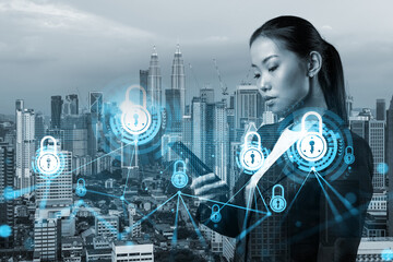 Attractive Asian cybersecurity developer explores new approaches to protect clients confidential information using phone. IT lock icons over Kuala Lumpur city background.