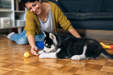 woman enjoying time with her siberian husky puppy at home