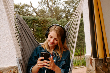 chica joven sonriente con auriculares escuchando música en el dispositivo electronico