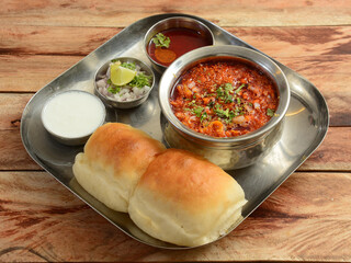 Misal Pav is a special dish in Maharashtra, India. The dish is eaten for breakfast or as a midday snack, served over a rustic wooden background, selective focus