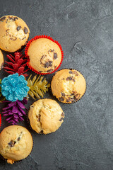 Obraz na płótnie Canvas Half shot of new year decorations around small cupcakes on dark background