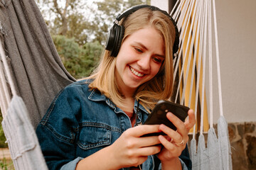 chica joven sonriente con auriculares escuchando música en el dispositivo electronico