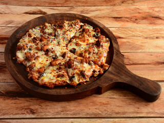Chicken Pizza on wooden pizza board, isolated over a rustic wooden background, selective focus