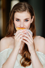 beautiful young woman with long hair and makeup eating a hamburger. 