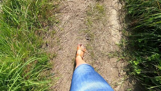 Woman walks along dirt path on a sunny summer day