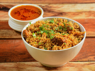 Mutton pulao cooked with masala spices, served over a rustic wooden background, selective focus