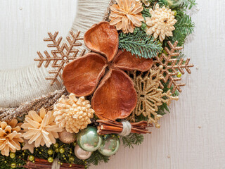 Part of Christmas decoration wreath with cones and Christmas toys on beige background