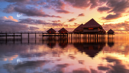 Tahiti bungalows with reflection in water during sunset