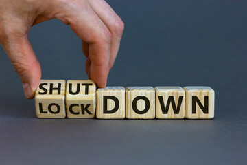 Lockdown or shutdown. Male hand flips wooden cubes and changes the word 'lockdown' to 'shutdown'....