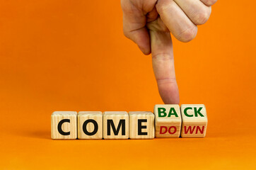 Comedown or comeback symbol. Male hand flips wooden cubes and changes the word 'comedown' to...
