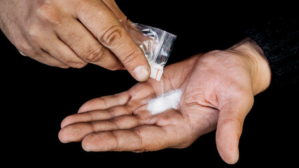 Man hand holding a plastic bag or bag with cocaine or other drugs, drug abuse and the danger of addiction concept.