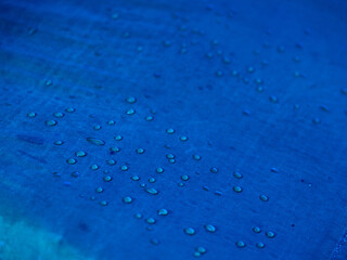 Water drops on waterproof membrane fabric. Detail view of texture of blue synthetic waterproof cloth. Morning dew on tent.