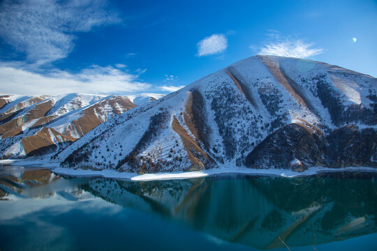 A lake high in the mountains in winter with the blue sky and reflection in the water