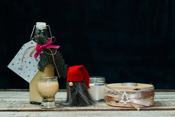 Homemade alcohol egg liquere with jar, candle and dwarf decoration on wood table
