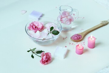 Fresh pink roses, water, petals, candles on a light background, body care products, natural home cosmetics, healthy lifestyle