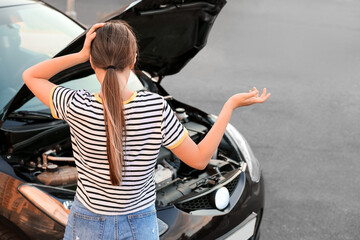 Stressed woman near broken car outdoors