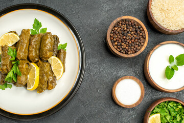 top view stuffed grape leaves wooden bowls with rice natural yogurt parsley black pepper salt on dark background