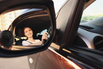 Beautiful woman with seat belt in car side mirror