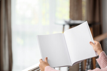 Young woman with blank magazine at home