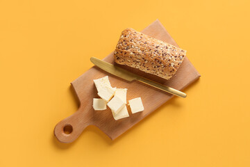 Chopping board with fresh butter and tasty bread on color background