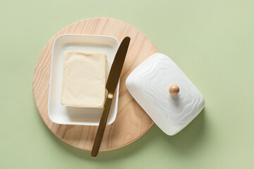 Chopping board with fresh butter on color background