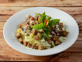 Classical Caesar salad, isolated over a rustic wooden background, selective focus