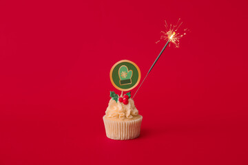 Tasty Christmas cupcake with sparkler on color background