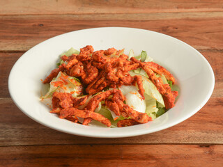 Warm chicken salad served over a rustic wooden background, selective focus