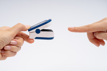 Fingertip Pulse Oximeter on finger. On white background. Device for self health diagnostic