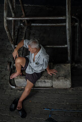 Bangkok, Thailand - July 10, 2019 : Senior man Sit and relax under basketball backboard at community stadium. No focus, specifically.