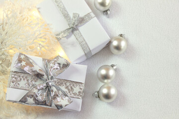 Bożonarodzeniowa srebrno-biała dekoracja z prezentami, bombkami i oszronionymi gałązkami

